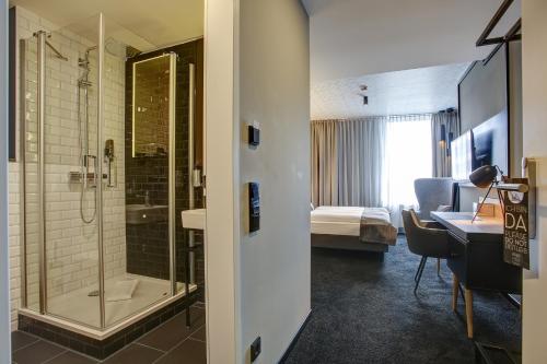 a hotel room with a shower and a bedroom at NYCE Hotel Dortmund City in Dortmund