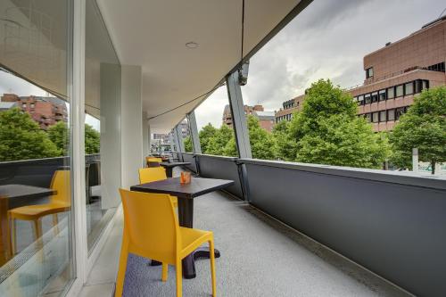 a table and chairs on a balcony with a view at Vienna House Easy by Wyndham Dortmund City in Dortmund
