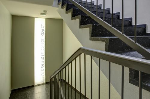 a staircase in a building with a sign on the wall at Vienna House Easy by Wyndham Dortmund City in Dortmund