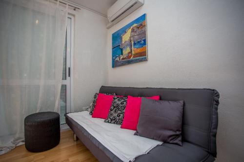 a living room with a gray couch with pink pillows at Apartments Lux in Makarska
