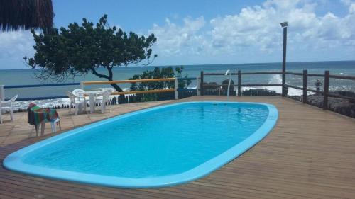 a large blue swimming pool on a deck with the beach at Casa Sol e Mar Beira-mar in Ilhéus