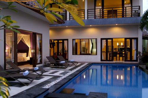 a villa with a swimming pool in front of a house at Villa Aamoda in Canggu