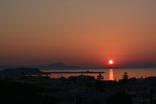 a sunset over the water with a city at Thegaia Studios in Rethymno Town