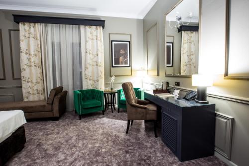 コンスタンツァにあるPeninsula Boutique Hotelのベッドとデスクが備わるホテルルームです。