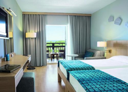 Habitación de hotel con 2 camas, escritorio y TV. en TUI BLUE Sarigerme Park en Dalaman