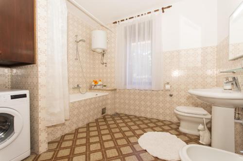 a bathroom with a toilet sink and a washing machine at Apartment Lorenzo in Trogir