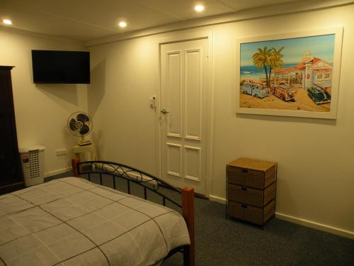American River的住宿－The Anchorage Cottage Kangaroo Island，卧室配有一张床,墙上挂有绘画作品