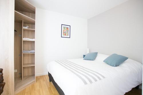 białe łóżko z niebieskimi poduszkami w sypialni w obiekcie Grain de Blé w mieście Mainvilliers