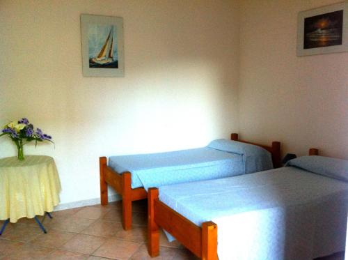 Zimmer mit 2 Betten und einem Tisch mit einer Blumenvase in der Unterkunft B&b Sa Domo in San Teodoro