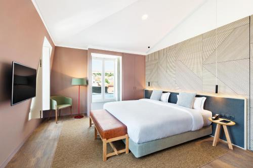 um quarto de hotel com uma cama grande e uma televisão em OnJ S. Lazaro Lisboa em Lisboa