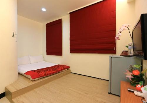 a bedroom with a bed with red sheets and a tv at Mei Lodge in Taipei