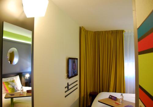 a room with a bed and a yellow curtain at ibis Styles Roanne Centre Gare in Roanne