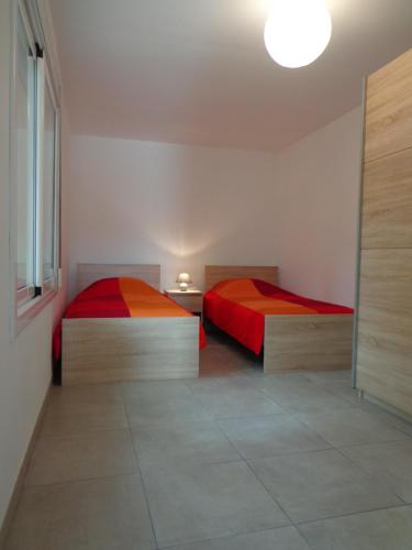 ペレジョにあるApartamento Tramuntanaの赤とオレンジのシーツが備わるベッド2台(1室あたり)