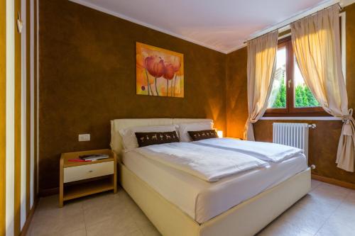 a bedroom with a large white bed with a window at Residence Rta La Rosa delle Dolomiti in Carisolo