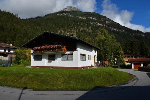 a white house with a mountain in the background at Ferienwohnung Frauenschuh in Vorderhornbach