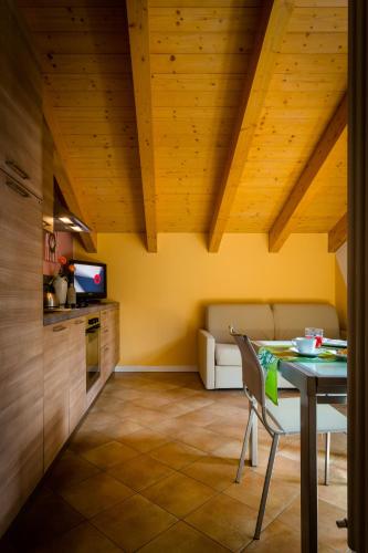 a kitchen with yellow walls and a table with a chair at Residence Rta La Rosa delle Dolomiti in Carisolo