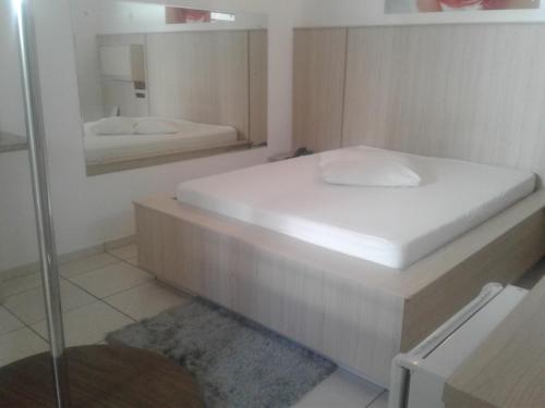 a small bedroom with a bed and a mirror at Prime Motel in Criciúma
