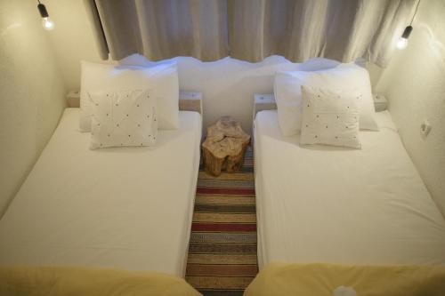 two beds in a small room with white sheets and pillows at Apartment Raza in Konjic