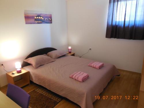 a bedroom with a bed with two pink pillows on it at Sobe Žalac in Karlovac
