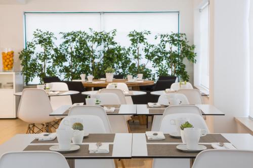 a dining room with tables and white chairs and plants at Hotel Alcatruz in Aljezur