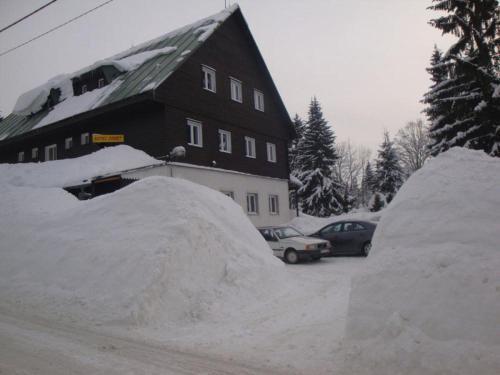 a pile of snow next to a house and two cars at Horsky hotel Sport in Josefuv dul