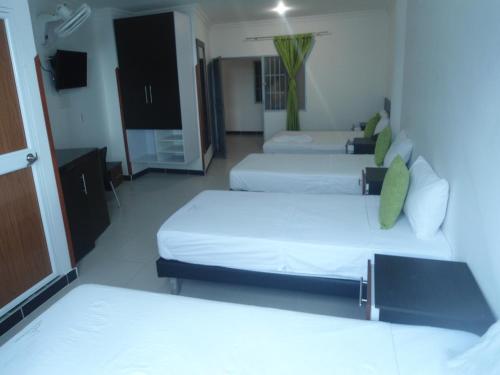 a room with three beds and a tv in it at Hotel El Principe Sede Campestre in Ocaña