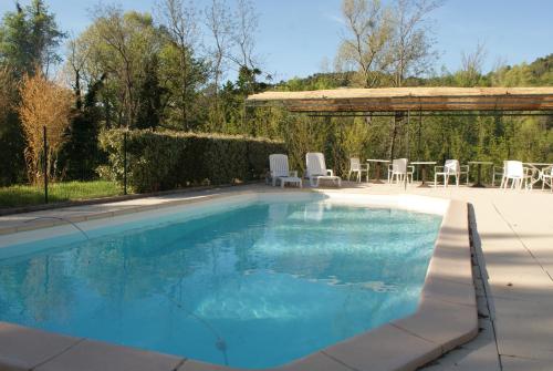 a large swimming pool with a table and chairs at Villa Les Carlets in Saignon