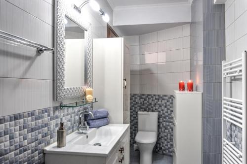 a bathroom with a sink and a toilet and a mirror at Kouros Studios in Kavála
