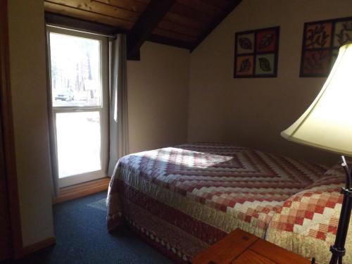 a bedroom with a bed with a lamp and a window at Arizona Mountain Inn & Cabins in Flagstaff
