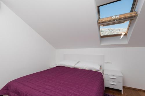 een slaapkamer met een paars bed en een raam bij Apartman Marica in Orebić