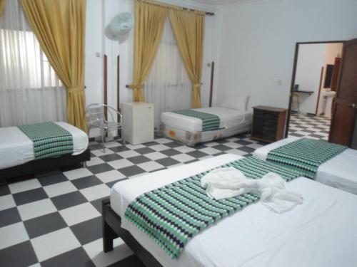 a bedroom with two beds and a checkered floor at Hotel El Principe Sede Campestre in Ocaña