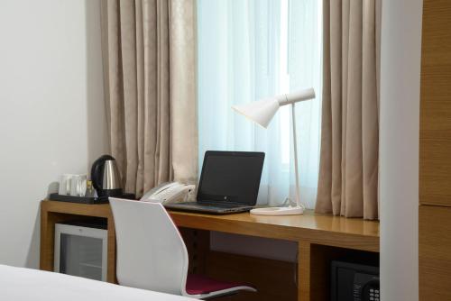 a desk with a laptop computer and a phone at ibis Styles Manama Diplomatic Area in Manama