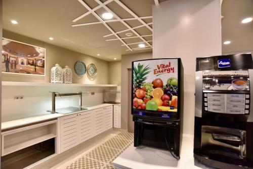 a kitchen with a refrigerator with a fruit display at TC Hotel Doña Luisa in Las Palmas de Gran Canaria