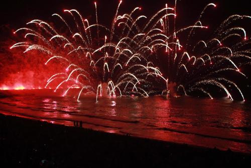 a firework display on the water at night at El Faro Apartaments in Tarragona