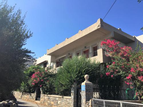 a house with pink flowers in front of a fence at Janet's Apartments Elounda in Elounda