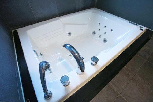 a white bath tub with two faucets in a bathroom at Friendly DH Naissance Hotel by Mindrum Group in Seoul