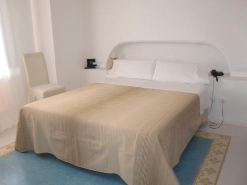 a bedroom with a white bed and a chair at Hotel Santa Marina Antica Foresteria in Santa Marina Salina
