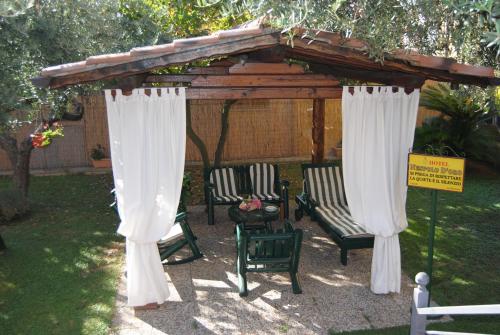 a gazebo with two chairs under it with curtains at Hotel Nespolo D'Oro in Lariano