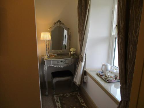 a hallway with a table with a mirror and a chair at White Lodge B & B in Strathpeffer