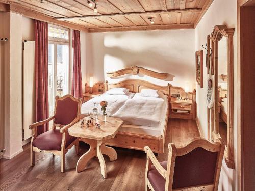 una camera con letto, tavolo e sedie di Hotel Schönegg a Wengen