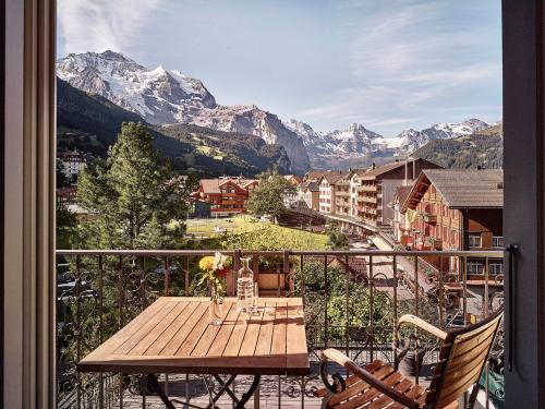a table on a balcony with a view of mountains at Hotel Schönegg in Wengen