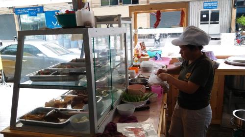 a woman standing in front of a food stand at Natcha Place Rangsit Donmuang in Ban Talat Rangsit