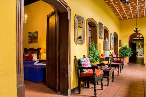 einen Flur mit Stühlen und ein Zimmer mit einem Bett in der Unterkunft Hotel Casa Antigua by AHS in Antigua Guatemala