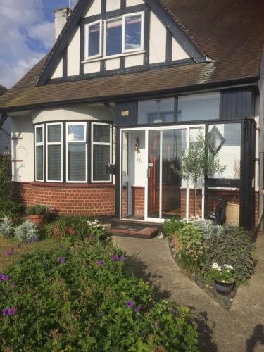 a house with glass doors and flowers in the yard at Southend Airport Bed & Breakfast in Rochford