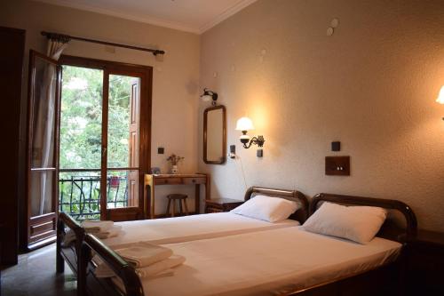 a bedroom with two beds and a window with a balcony at Pension Felippe in Pythagoreio