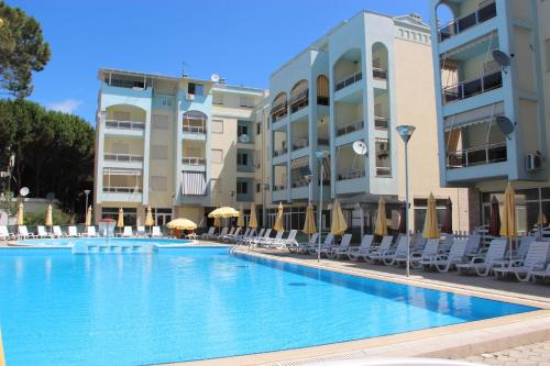 uma piscina com cadeiras e guarda-sóis em frente aos edifícios em Golem Apartments em Golem