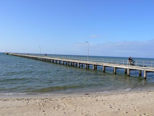 a person standing on a pier over the ocean at Rosebud Beach Unit 200 mt to Beach Late checkout in Rosebud