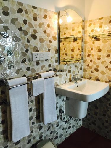 a bathroom with a sink and a mirror and towels at Randiya Beach Villa in Galle