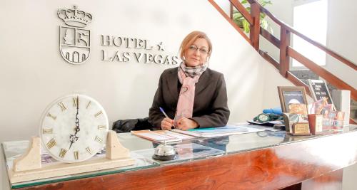 una mujer sentada en un escritorio con un reloj en Las Vegas Hotel Termal en Termas de Río Hondo