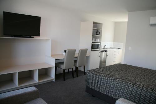 ein Hotelzimmer mit einem Bett und einem Schreibtisch mit einem TV in der Unterkunft Oxford Village Motels in Oxford
